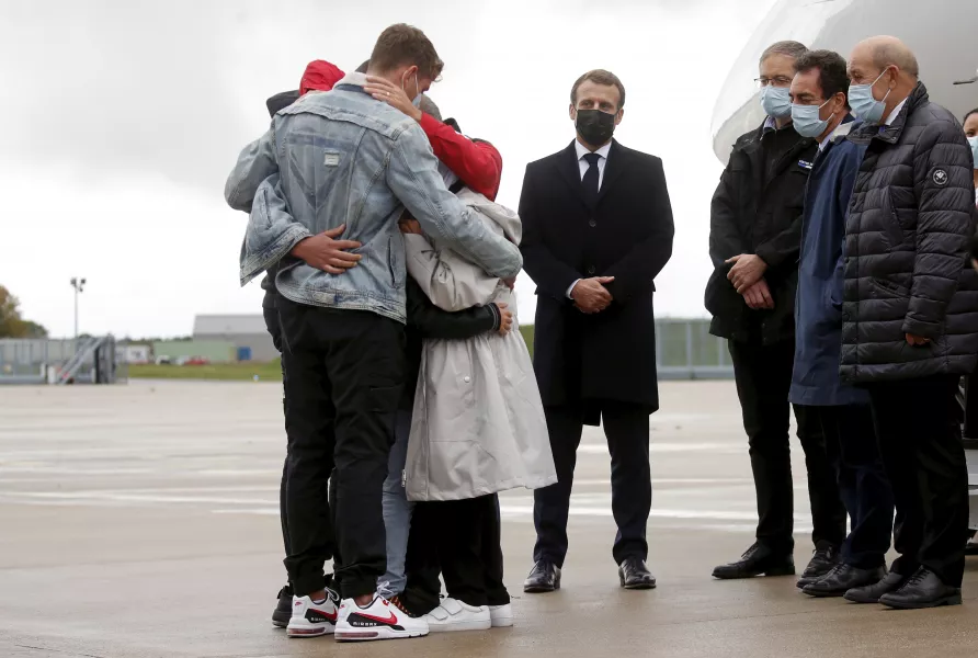 Emmanuel Macron stands as Sophie Petronin is greeted by relatives (Gonzalo Fuentes/AP)