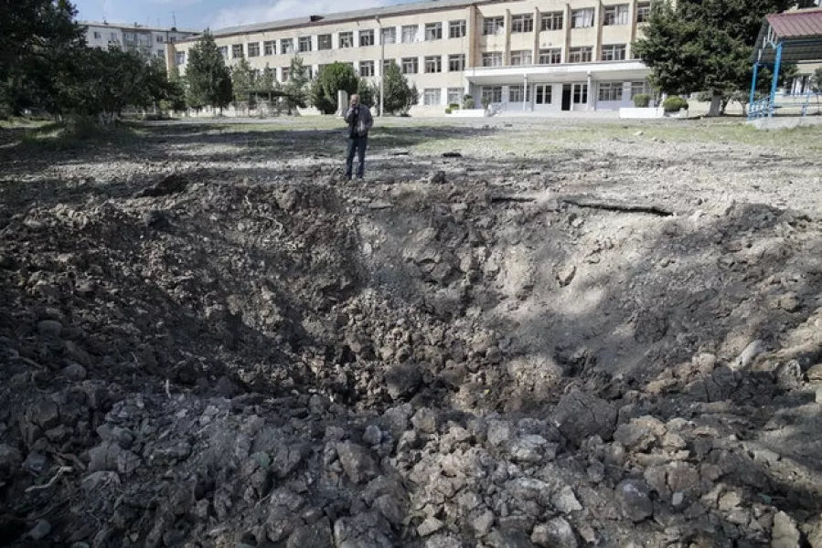 A man stands near an explosion crater near a school in Stepanakert, the separatist region of Nagorno-Karabakh (AP Photo)