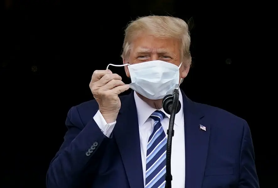 With two bandages on his hand, President Donald Trump removes his face mask (Alex Brandon/AP)