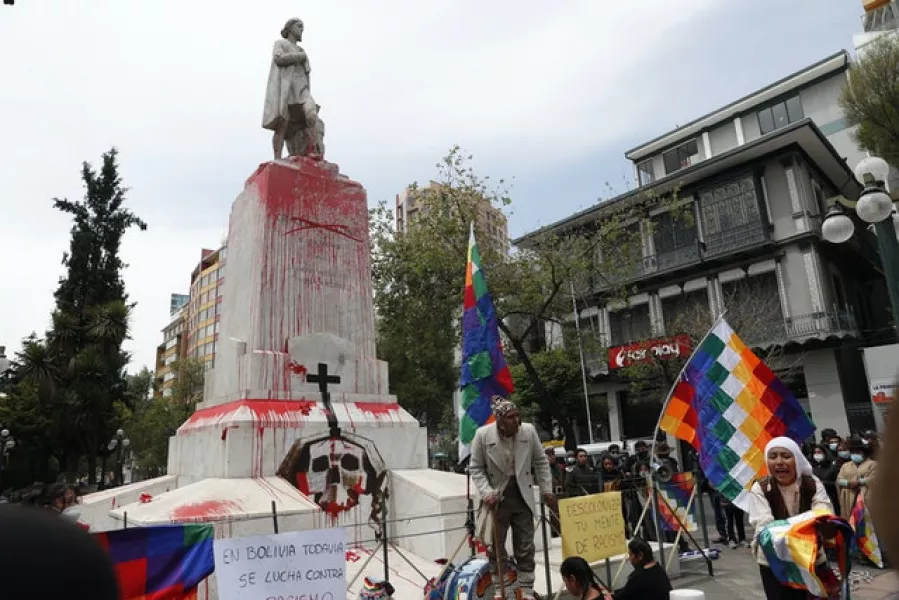 Activists protest Spanish colonization at the Christopher Columbus monument which they painted red to symbolize blood in La Paz, Bolivia, on Monday (Juan Karita/AP)
