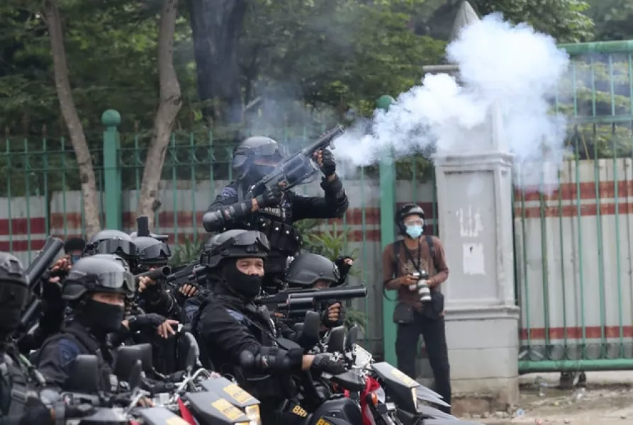 A police officer fires tear gas during the protests (AP/Tatan Syuflana)