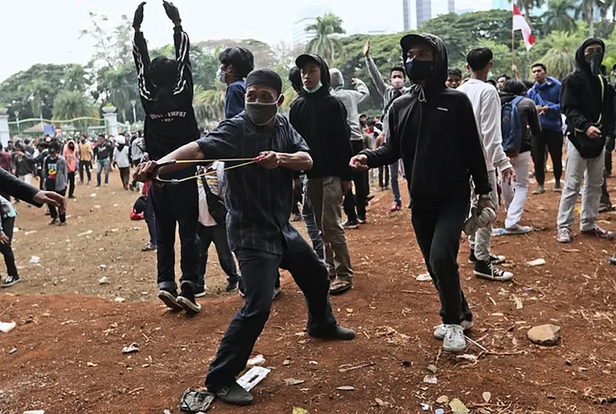 A protester shoots a slingshot at riot police (AP/Tatan Syuflana)