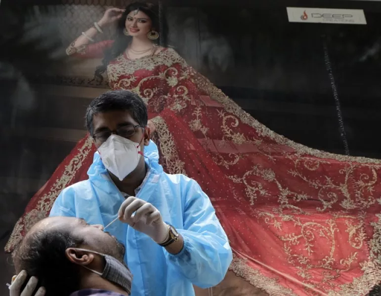 A health worker takes swab sample of a woman to test for Covid-19 outside a garment shop in Mumbai, India (Rajanish Kakade/AP)