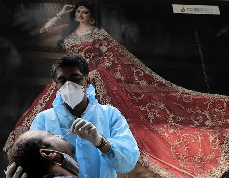 A health worker takes swab sample of a woman to test for Covid-19 outside a garment shop in Mumbai, India (Rajanish Kakade/AP)