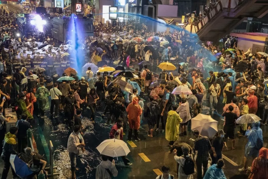 Umbrellas are used as a defence against water cannons (Gemunu Amarasinghe/AP)