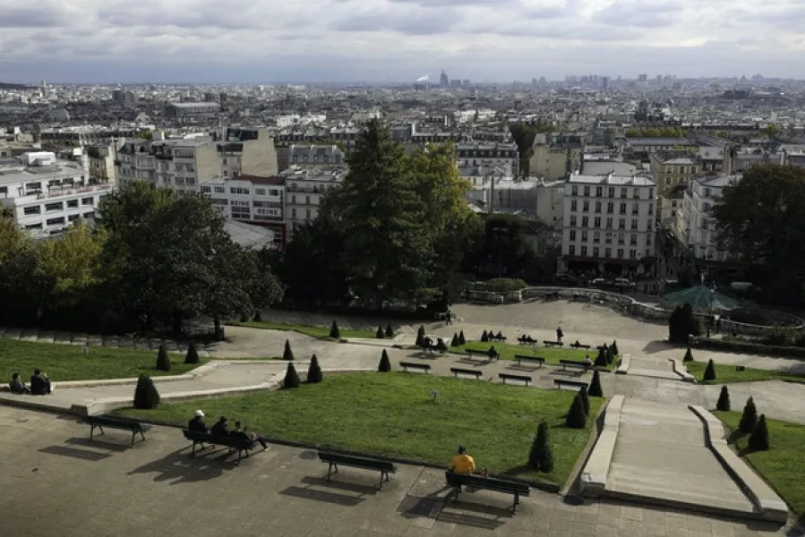 People sit in the gardens below the Sacre Coeur basilica in the Montmartre district of Paris (Lewis Joly/AP)