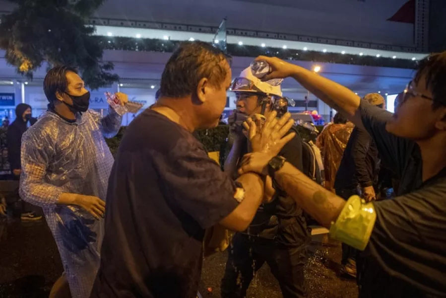 Pro-democracy demonstrators wash their eyes with fresh water after facing police water cannon (AP)