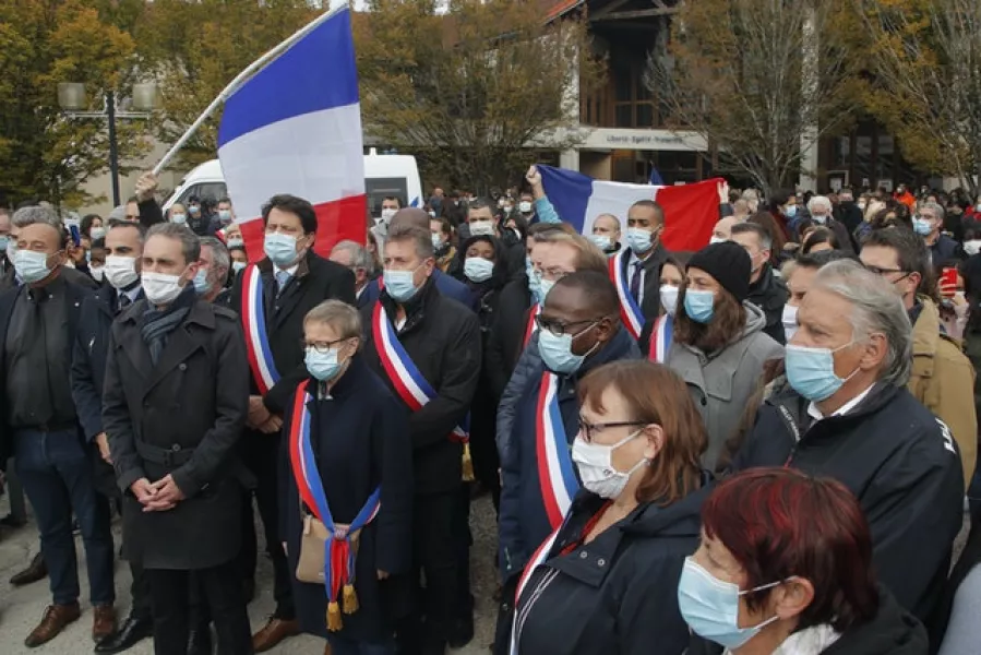 Local officials sing the national anthem outside the school in Conflans-Sainte-Honorine where teacher Samuel Paty was murdered (Michel Euler/AP)