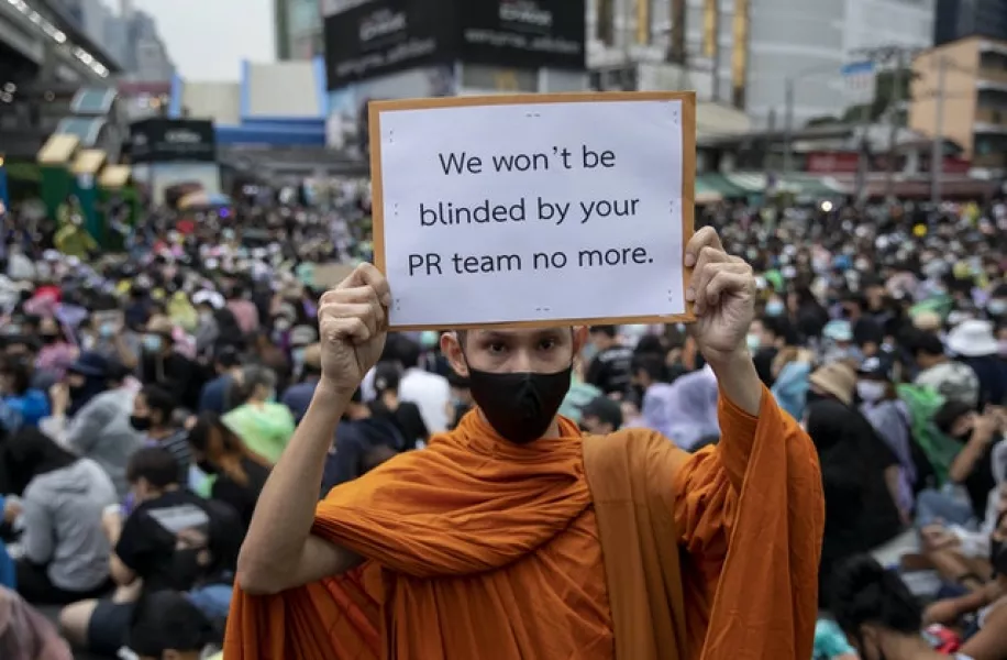 A Buddhist monk holds a poster during a protest rally in Bangkok (Gemunu Amarasinghe/AP)