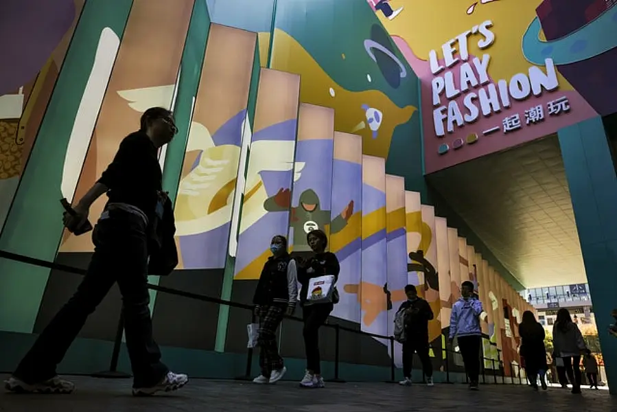 Shoppers wearing face masks to help curb the spread of the coronavirus walks through the capital city’s popular shopping mall in Beijing (AP)