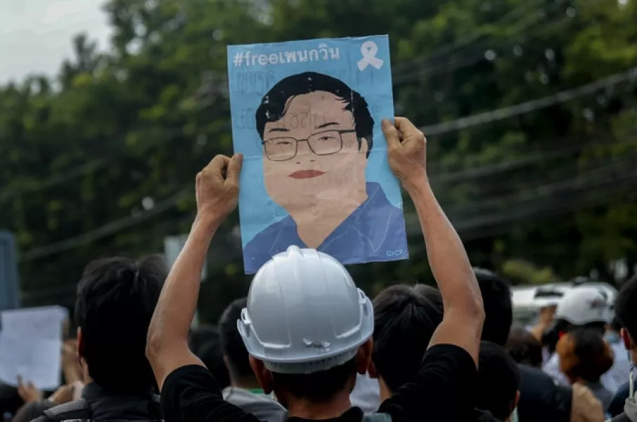 A pro-democracy activist displays a poster featuring an image of detained protest leader Parit ‘Penguin’ Chiwarak during a demonstration in the suburbs of Bangkok (Sakchai Lalit/AP)