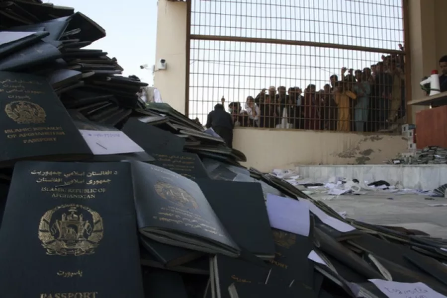 Afghans wait to collect their passports with Pakistani visas in the city of Jalalabad east of Kabul, Afghanistan (Wali Sabawoon/AP)