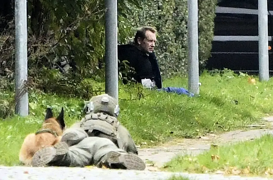 A police officer watches Peter Madsen as he sits on the side of a road after being apprehended (Nils Meilvang/Ritzau Scanpix/AP)