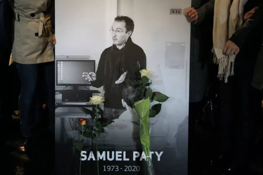 People hold a photo of teacher Samuel Paty during a memorial march (Lewis Joly/AP)