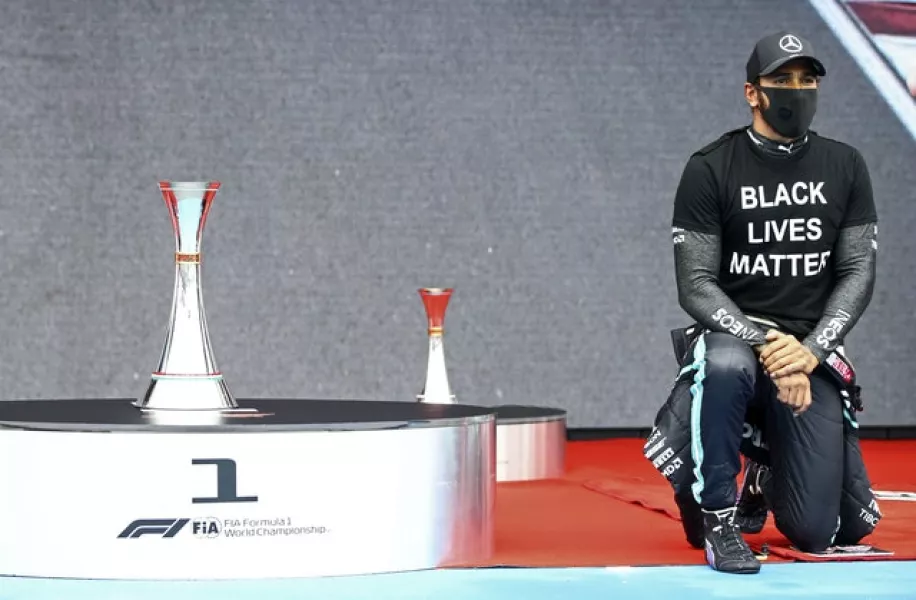 Hamilton takes the knee beside the trophy (Mark Thompson/Pool via AP)