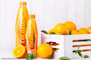 Lucozade Orange drinks with fresh oranges around