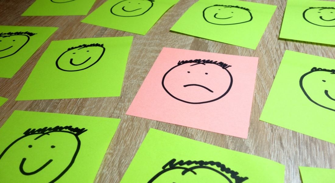 Sticky notes depicting one sad face surrounded by happy faces symbolising someone in the wrong company culture.