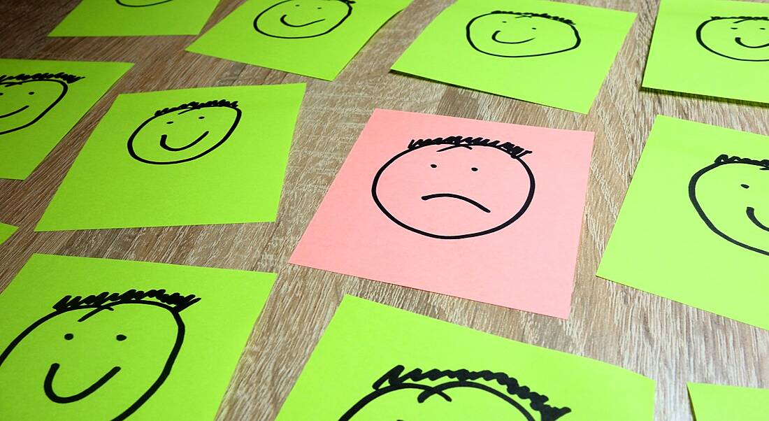 Sticky notes depicting one sad face surrounded by happy faces symbolising someone in the wrong company culture.