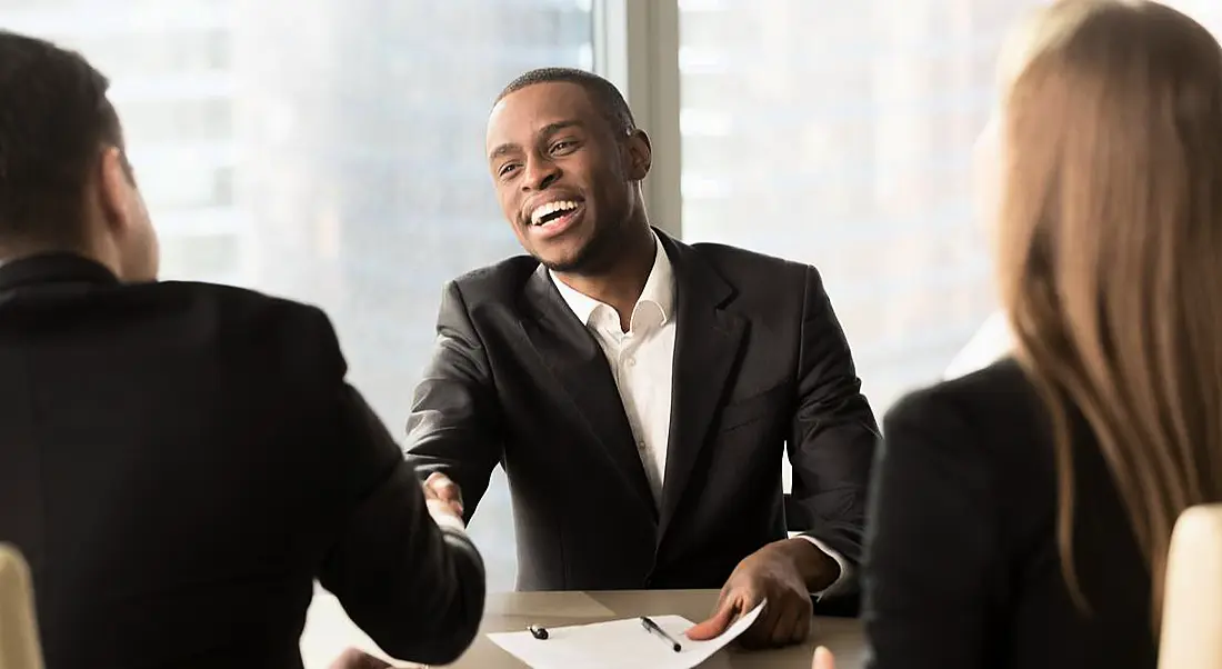 Excited businessman shaking hands with someone after being given a promotion.