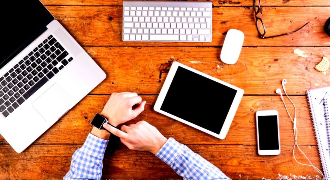 Business person working at office desk wearing smart watch. Workplace wearables, wearables in the workplace.