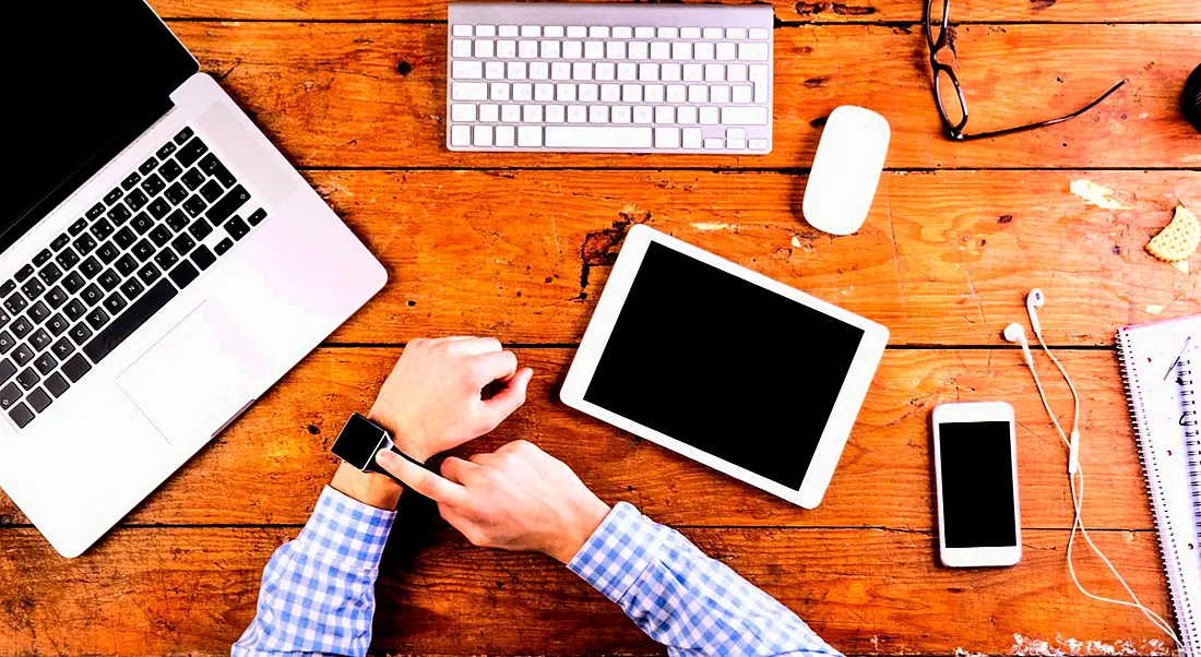 Business person working at office desk wearing smart watch. Workplace wearables, wearables in the workplace.