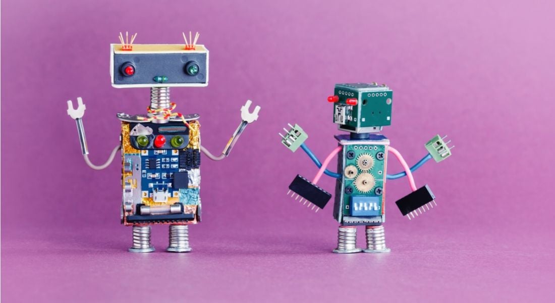 Two little robots on pink background AI artificial intelligence