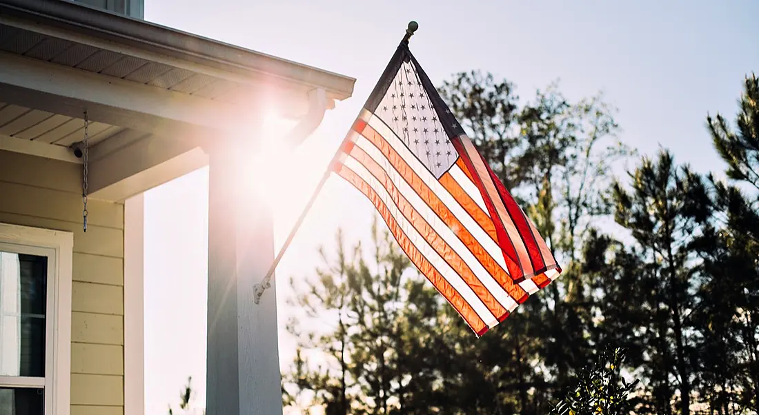 Front side of typical american porch colonial house with American flag out front. H-1B Visa Concerns