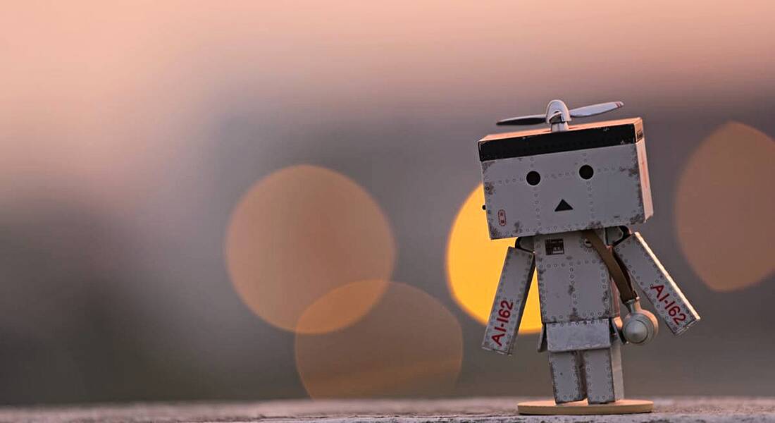 robot figure against the backdrop of a sunrise