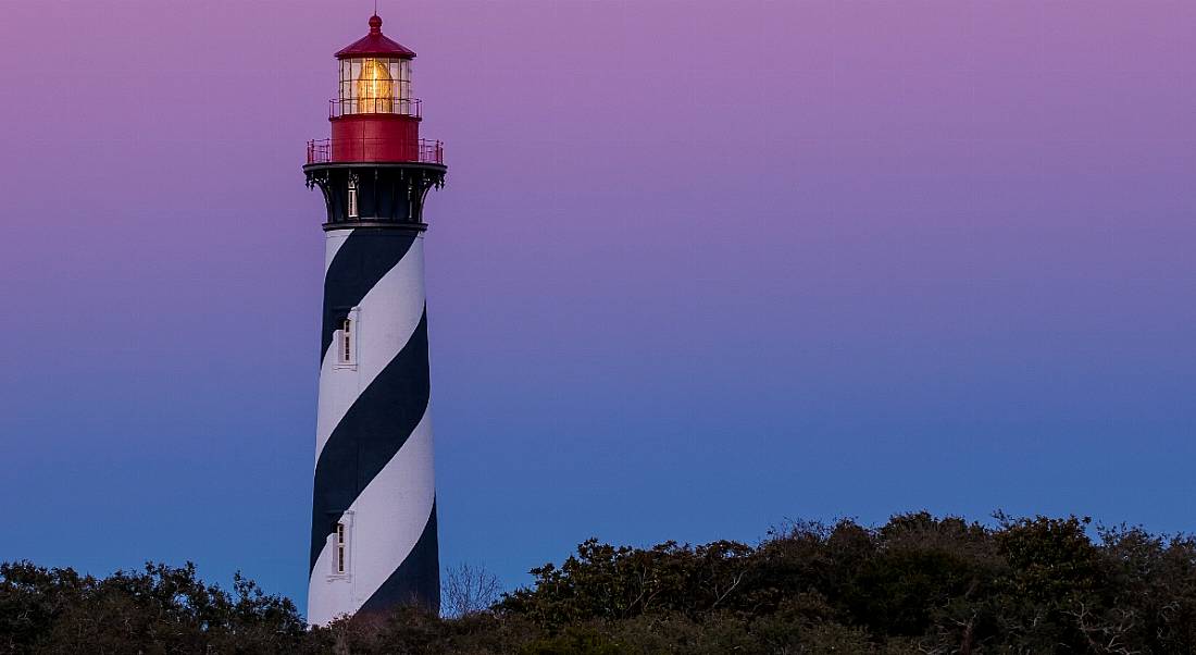 Lighthouse amid the reeds off the coast of the sea at sunset. Concept of Mayday, distress signal, May jobs announcements. Image: Kent Weakley/Shutterstock