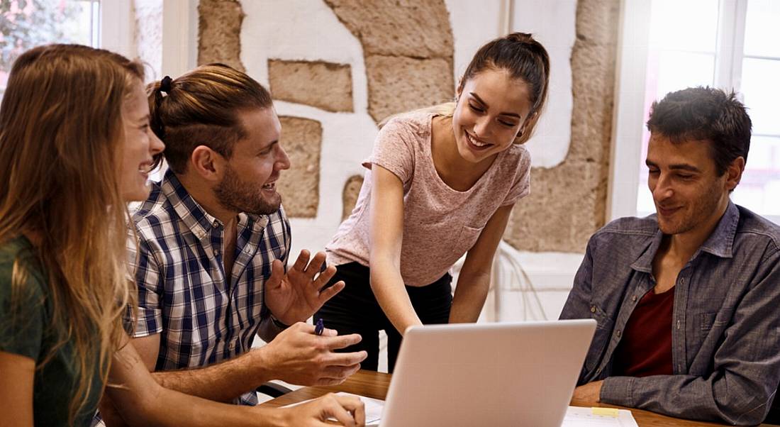 Millennials sitting around a laptop in lively and exciting discussion