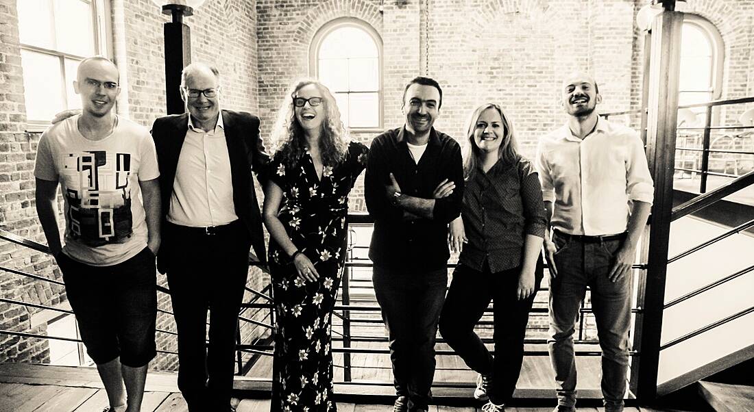 Members of the Opening.io team standing in a line in front a stairwell