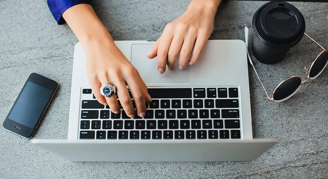 Aerial view of hands on a laptop to depict someone availing of free courses