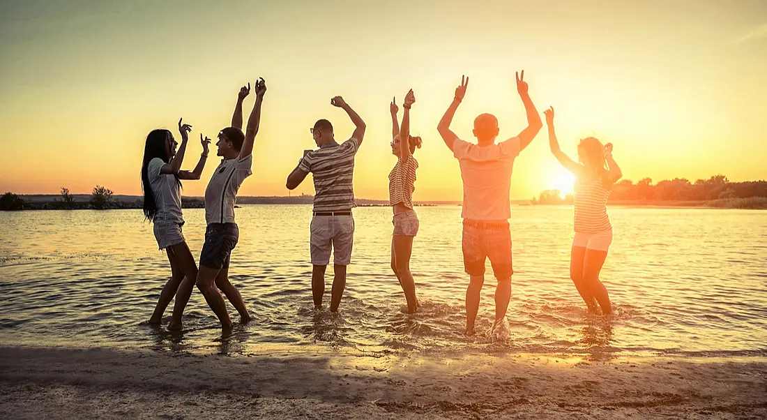 Silhouette of group young people on the beach under sunset sky with clouds at summer evening. Summery June sizzles with almost 3,500 jobs announced across Ireland