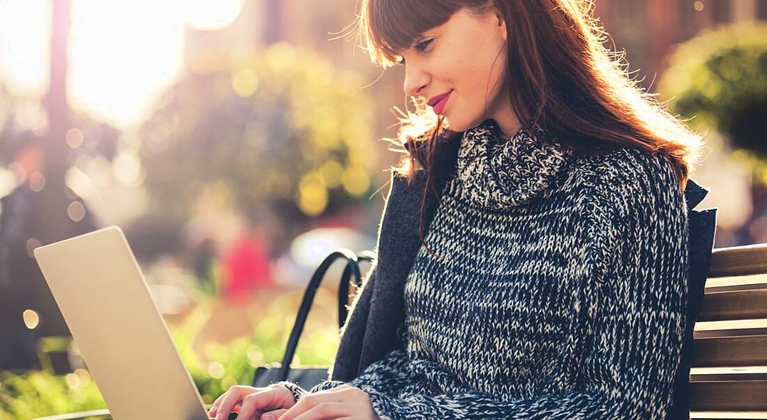 Woman on laptop in urban park, how to master your digital first impression