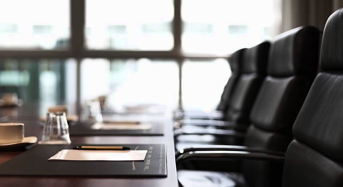 View of a meeting agenda sitting on a table lined with leather swivel chairs.