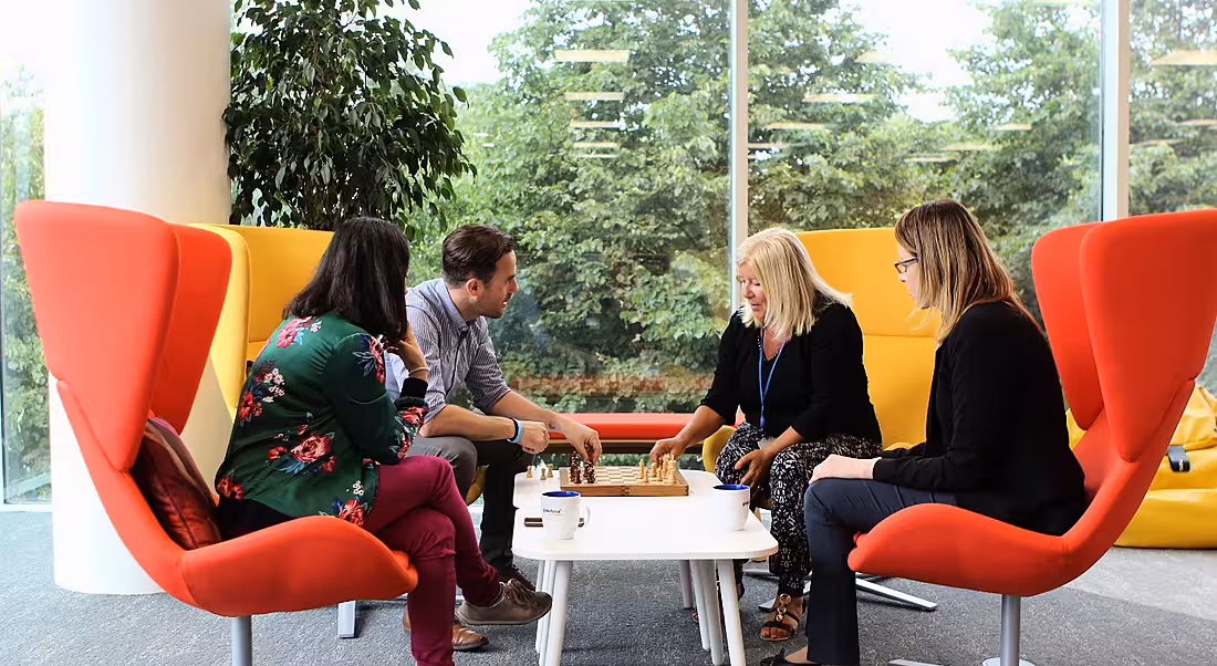 Four Workhuman employees sitting in colourful chairs playing chess