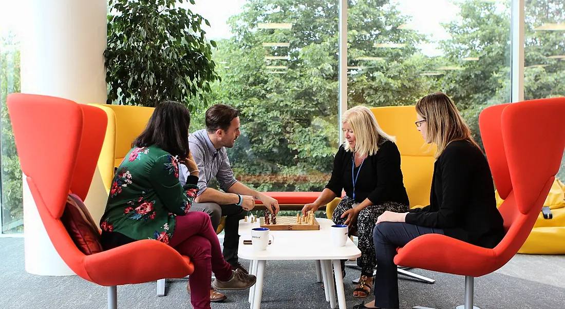 Four Workhuman employees sitting in colourful chairs playing chess