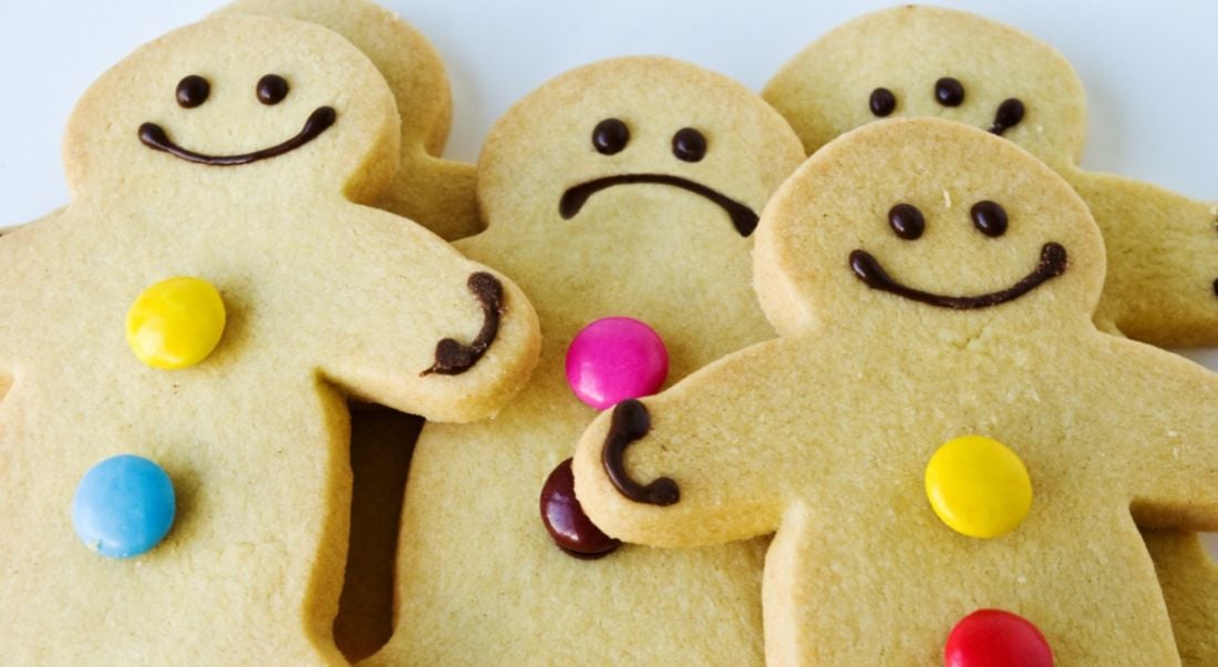 A group of smiling gingerbread men, but one among them is sad, clearly suffering from imposter syndrome.