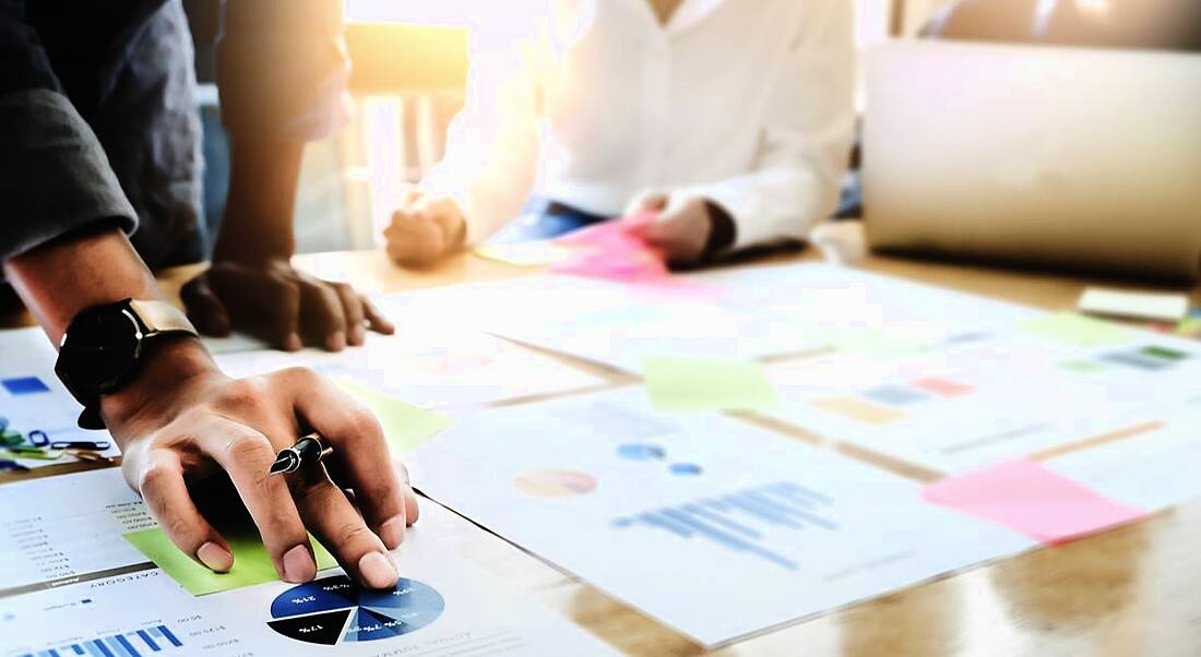 Man working on graphs and pie charts on a table, exercising his project management skills