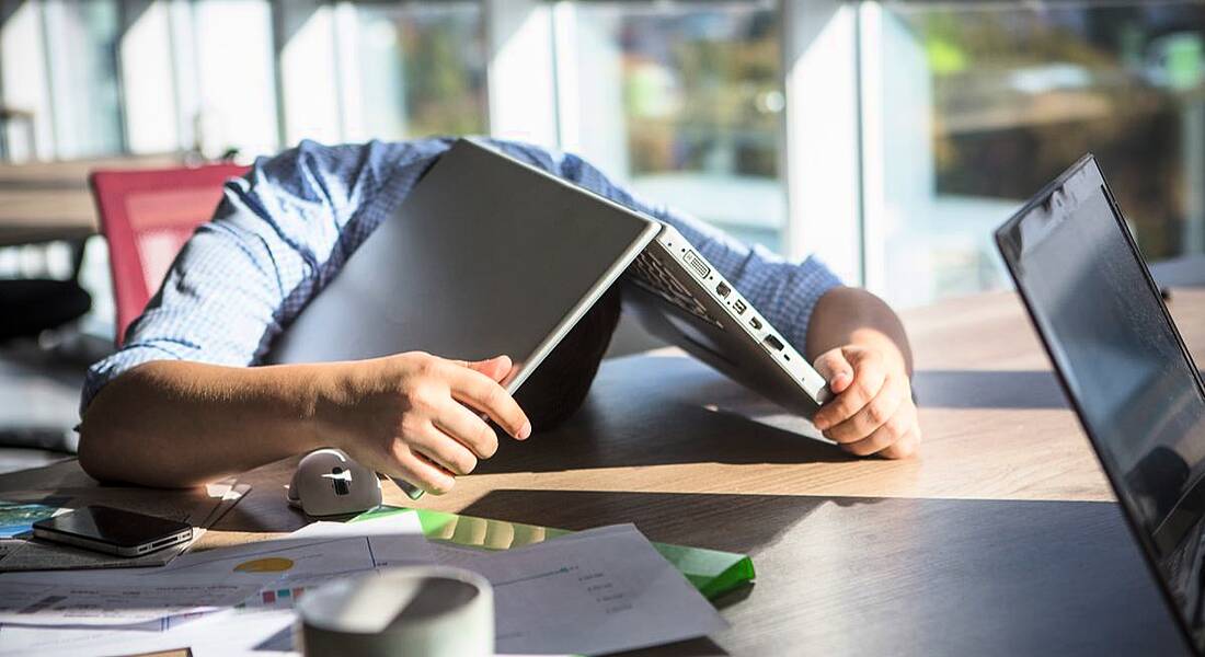 Man with laptop on top of head, such is the extent to which he is disengaged at work