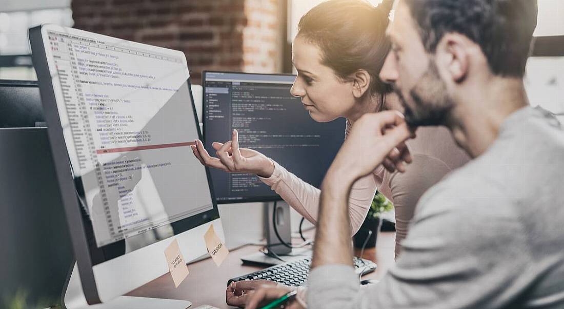 Man and woman gathered around screen doing software engineering, software engineering concept