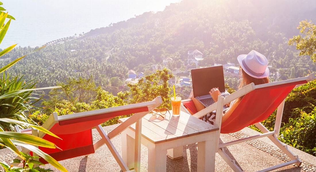 Girl working outside on laptop overlooking mountain view