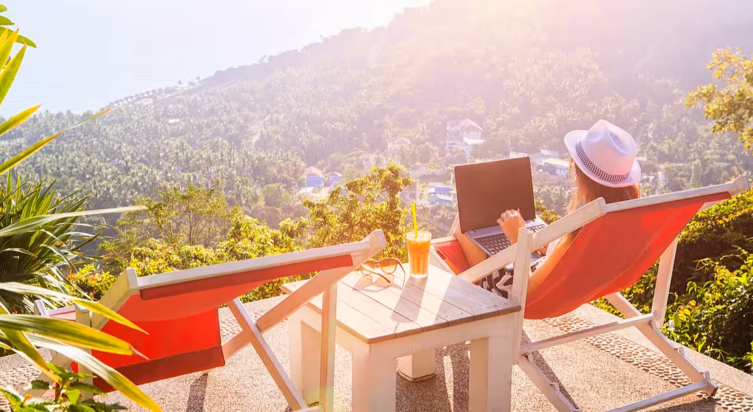 Girl working outside on laptop overlooking mountain view