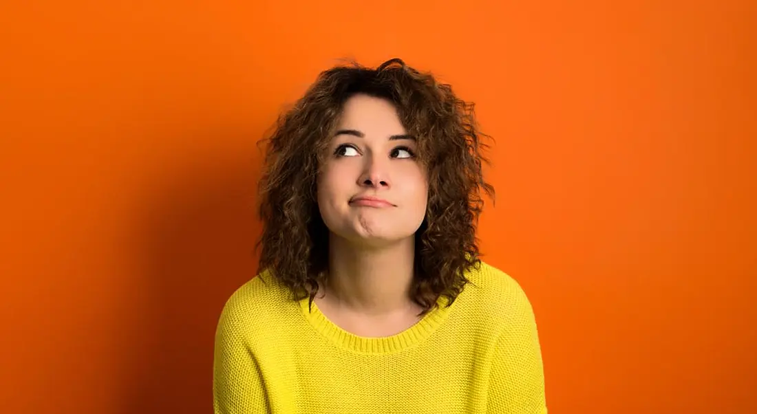 Women with yellow sweater on orange background contemplating how many jobs were created this week in Ireland