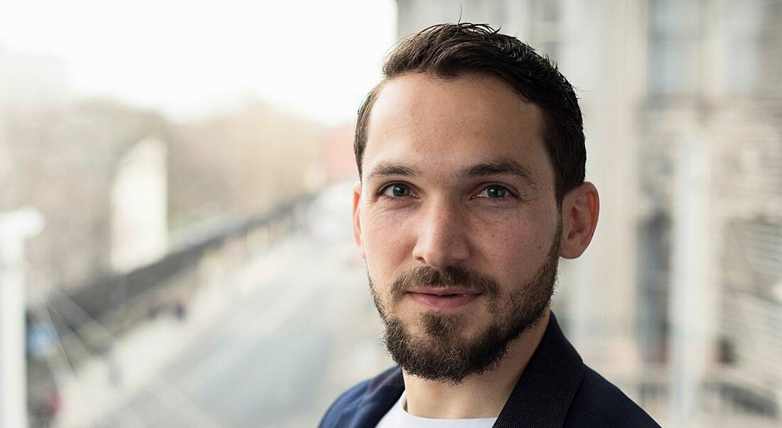 A young brown-haired man with a beard against the blurred-out backdrop of Dublin city. He’s a New Relic employee.