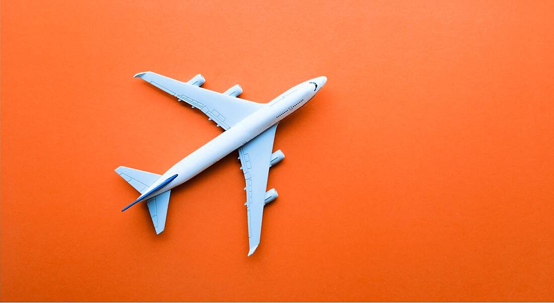 Aerial view of a toy aeroplane on a bright orange background.