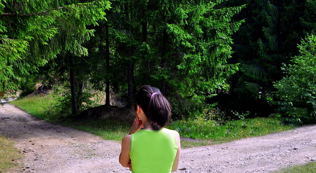 Young woman standing at fork in the road.