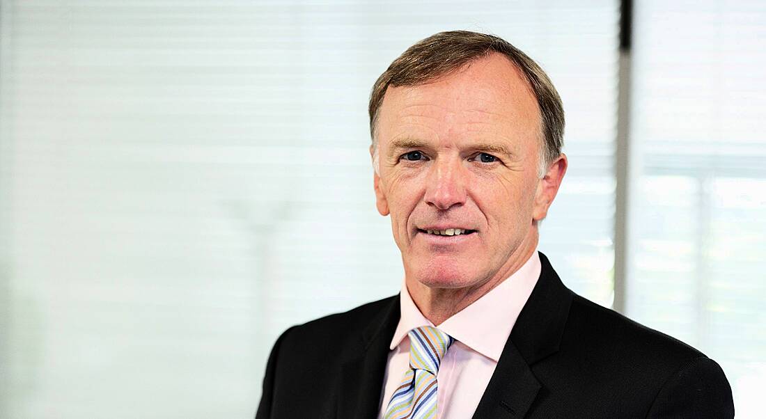 A man in his 50s staring straight into the camera wearing a dark-coloured business suit.