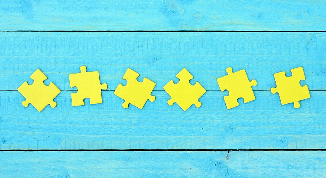 Six yellow jigsaw pieces arranged on a sky-blue wooden background.