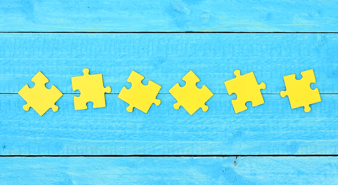 Six yellow jigsaw pieces arranged on a sky-blue wooden background.